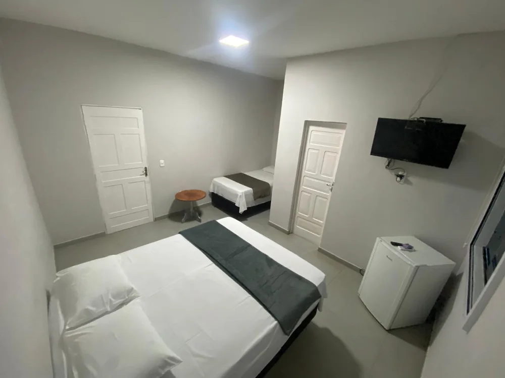 Suíte com cama de casal, cama de solteiro, TV e frigobar